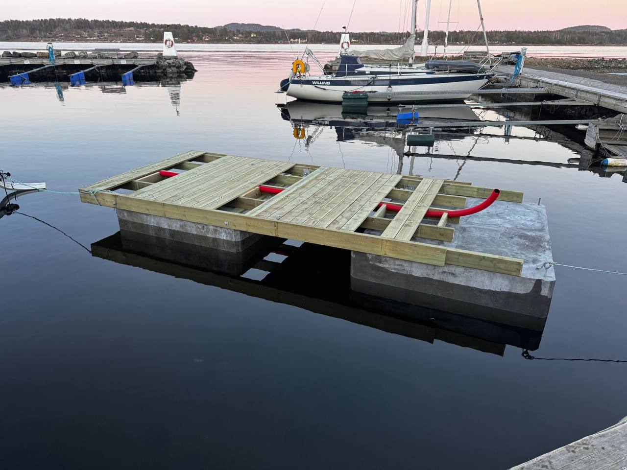 Flyteelement i betong med bjelkelag i tre, liggende i sjøen ved kai.